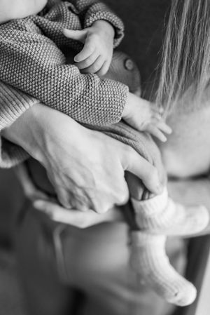 Black and white close-up of gentle hands holding infant feet.
