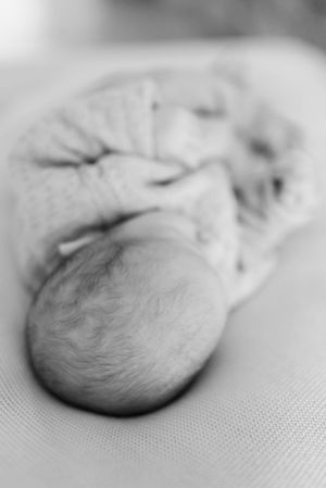 A black and white close-up image of a sleeping newborn infant.