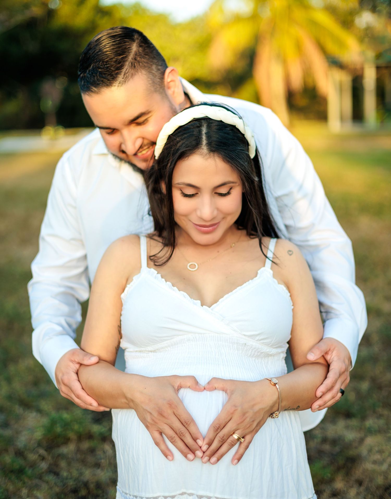 An intimate maternity photo showing a couple making a heart shape with their hands on her belly.