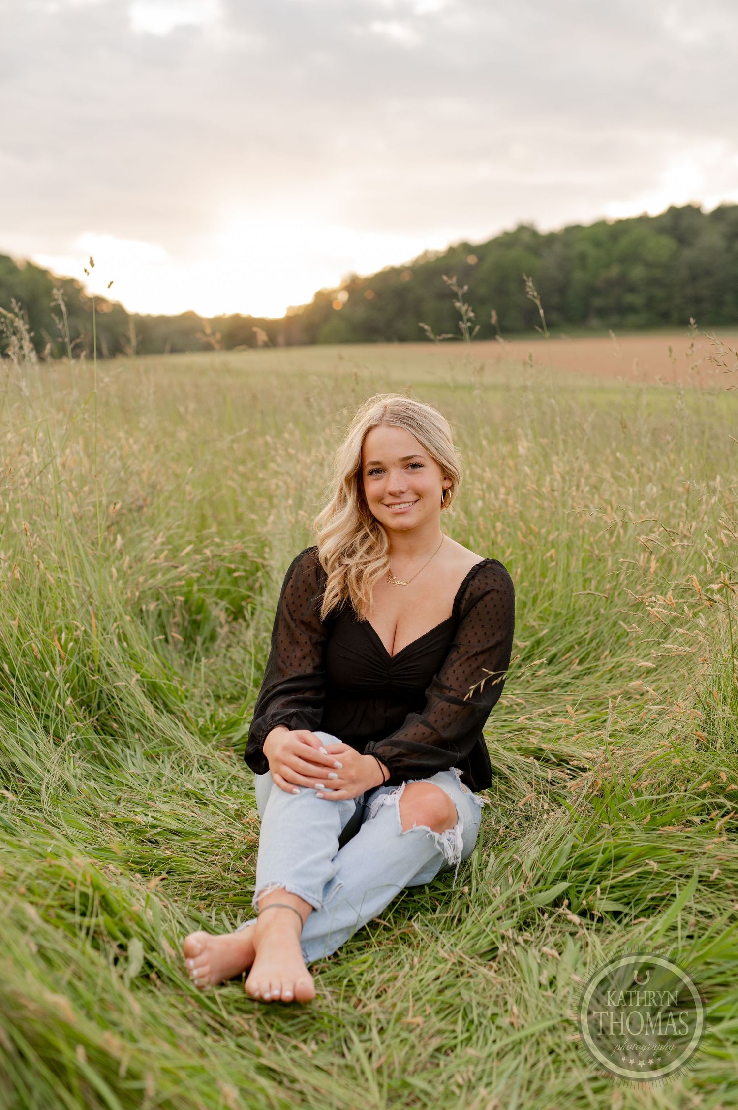 Relaxed outdoor portrait sitting in tall grass at golden hour.