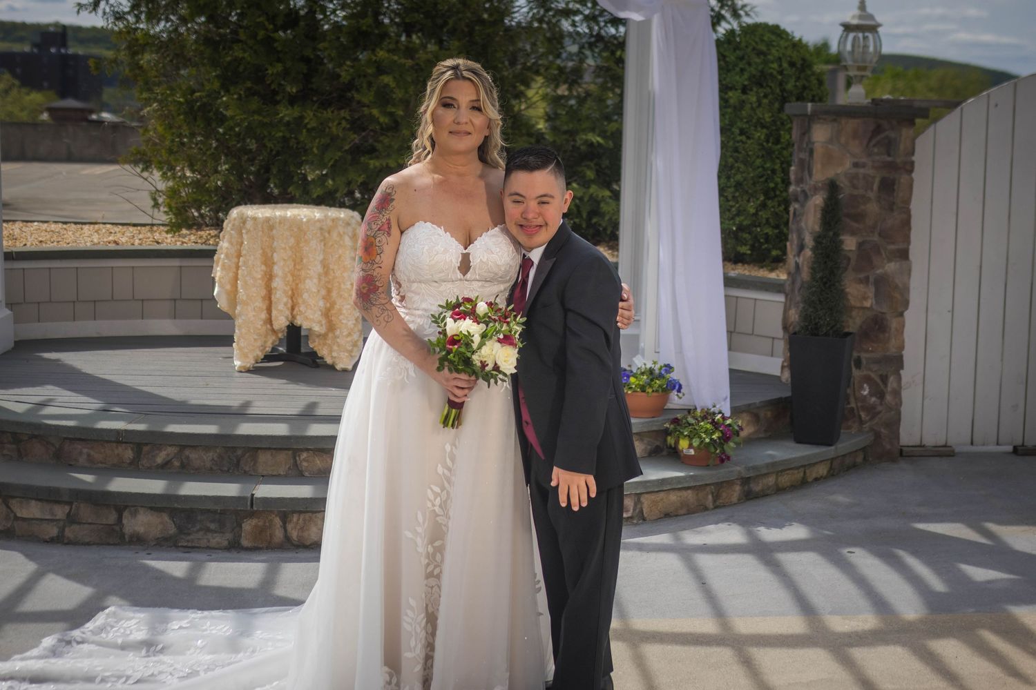Wedding couple poses for outdoor portraits near stone walls and greenery.