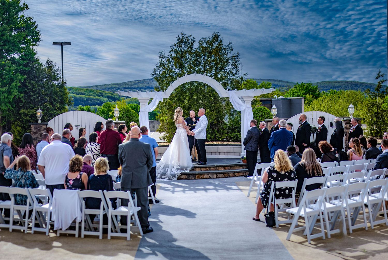 Outdoor wedding ceremony setup with white chairs and mountain views in the background.