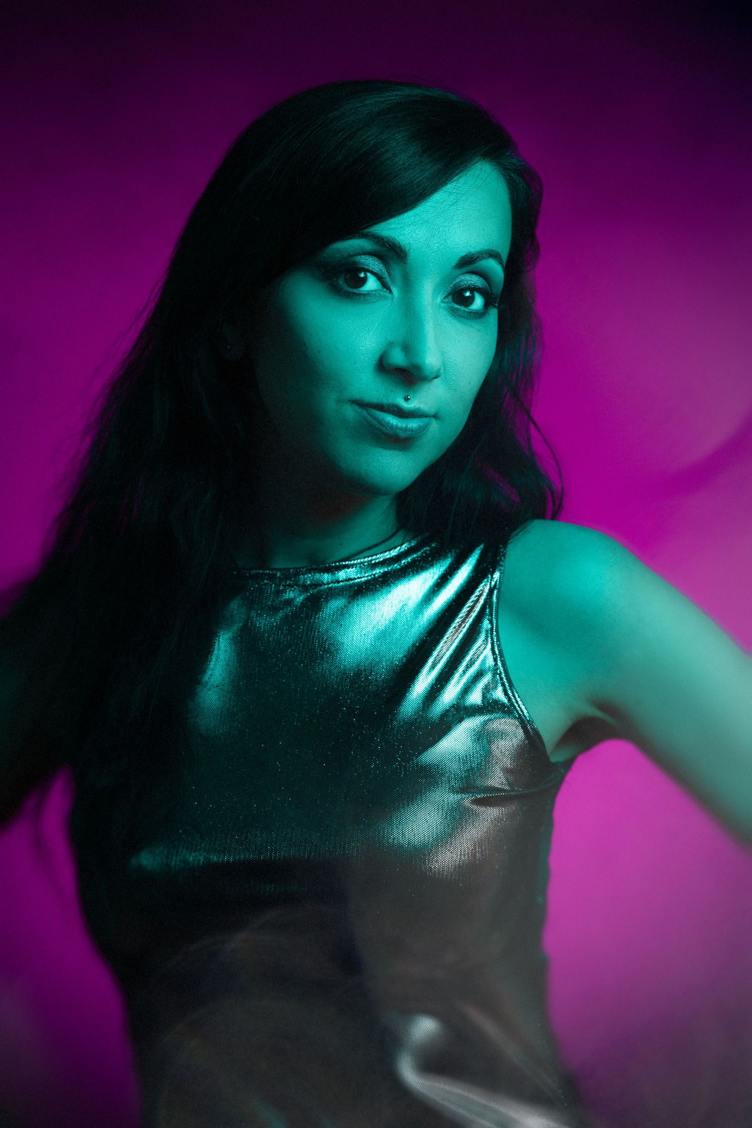 Artistic portrait with vibrant purple and teal lighting effects and metallic clothing.