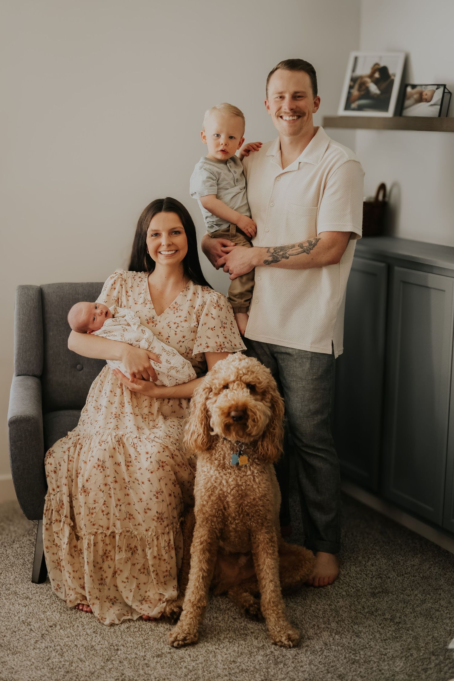 Family portrait with a goldendoodle dog, featuring parents with their children in a living room.