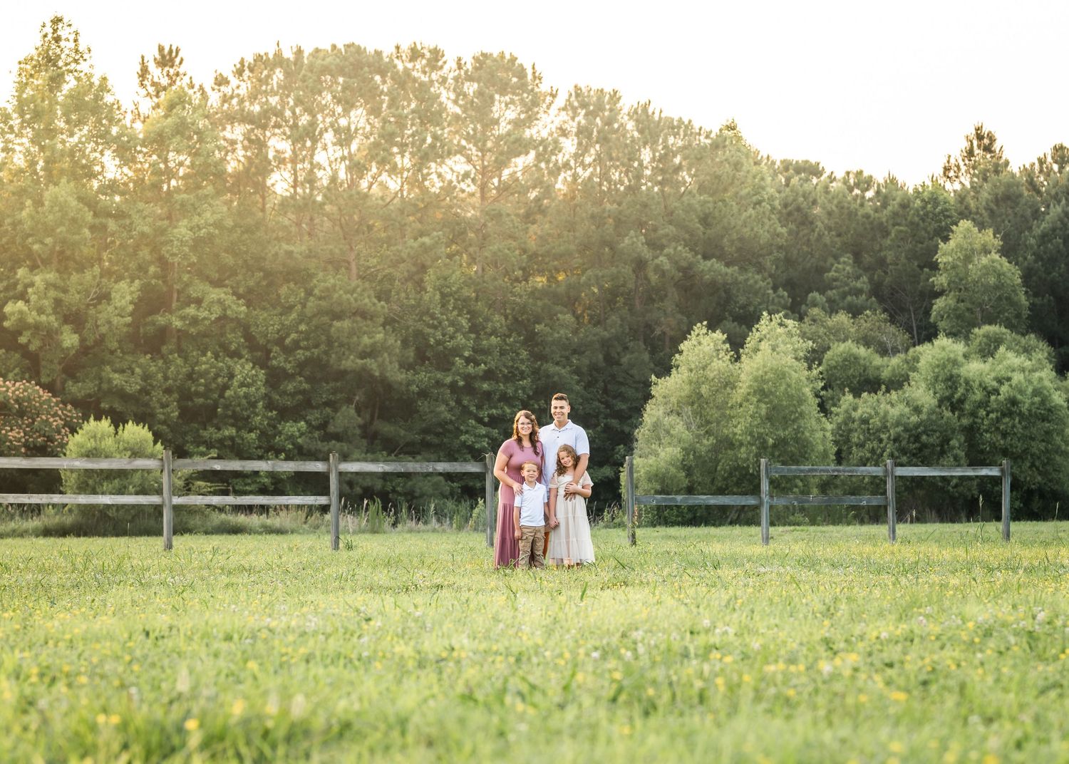 Family walking together in a golden sunlit meadow at sunset.