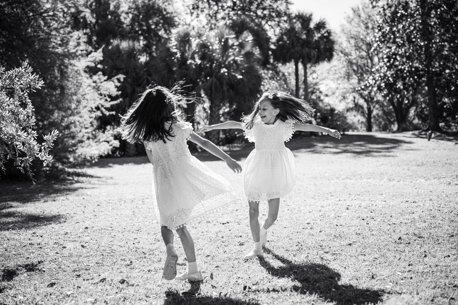 People playing and running through a sunlit garden in black and white.