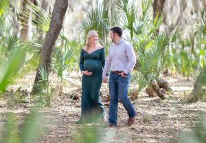 A couple walks hand in hand through a lush palm tree grove on a sunny afternoon.