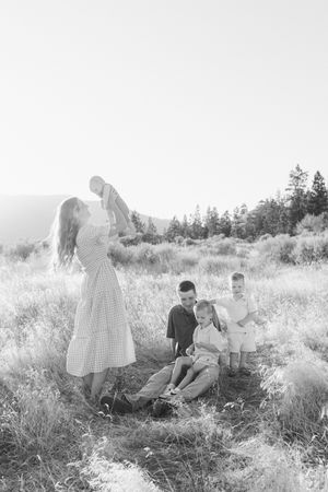 A family sits together in a sunlit meadow during a casual outdoor photo session.