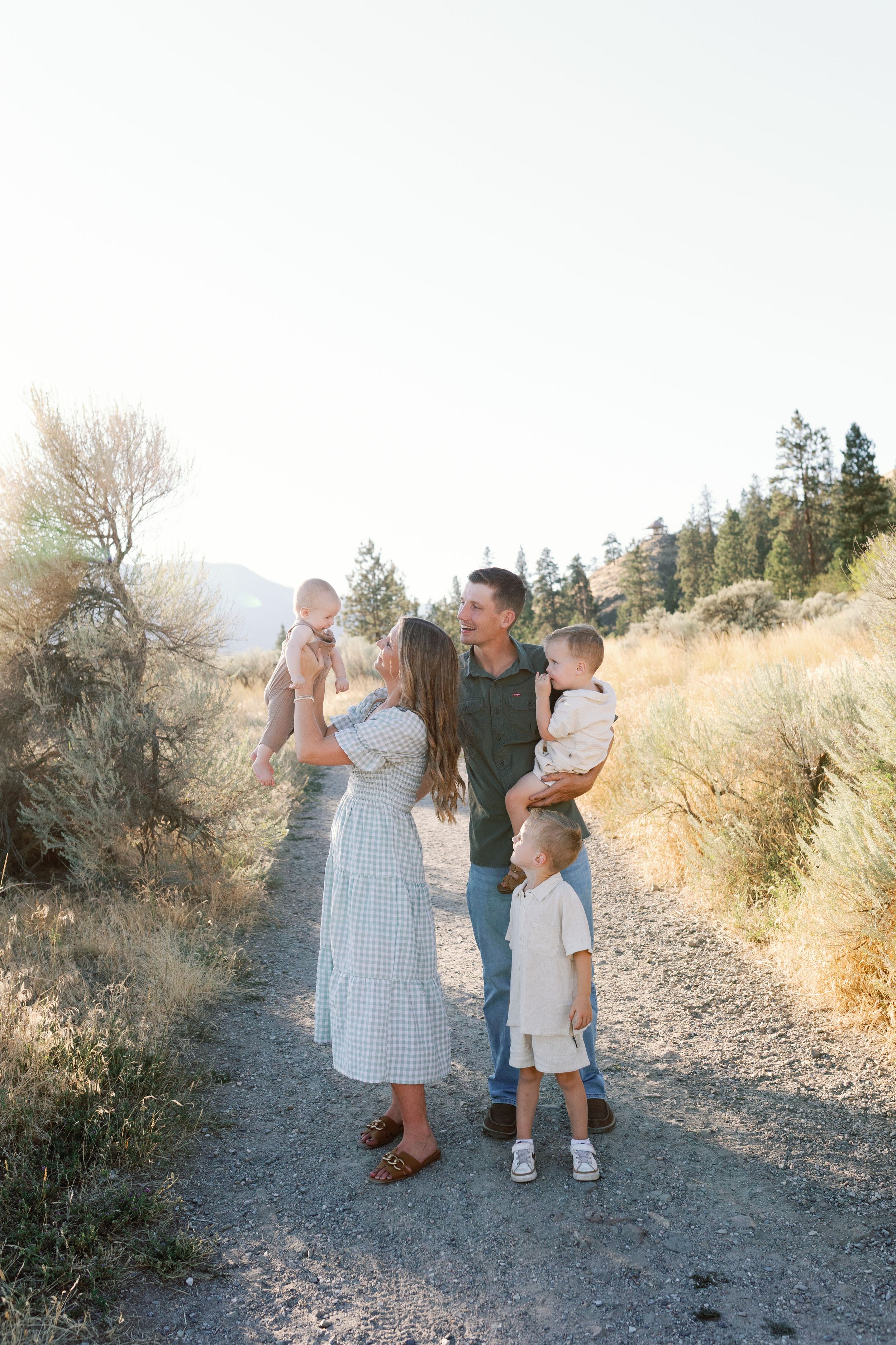 Family enjoying time together on a scenic mountain trail during golden hour sunset at an outdoor location.