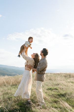 A couple shares romantic dance poses together in a sunlit meadow with mountains in the background.