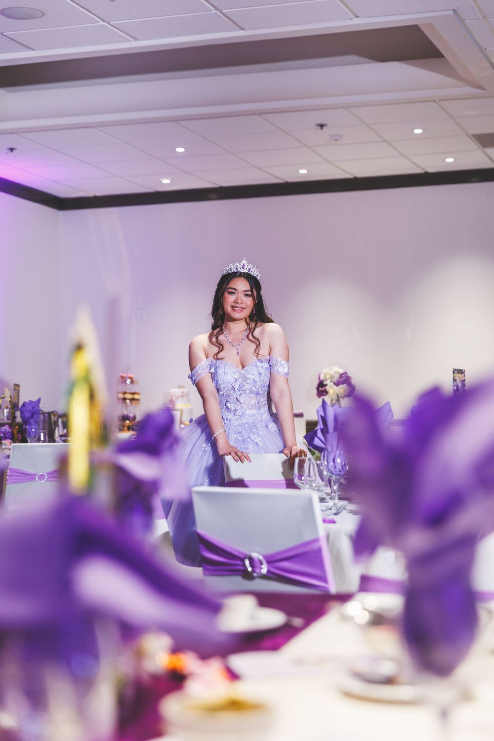 Purple table settings and decor create an elegant atmosphere at a wedding reception with blurred floral centerpieces.