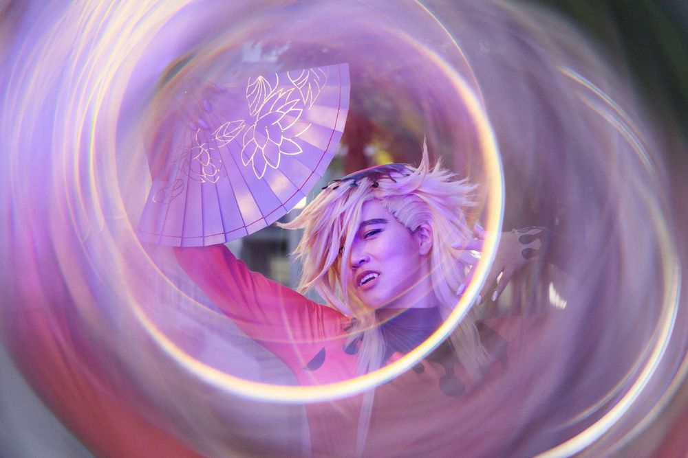 Abstract swirling purple and pink photo with circular motion blur effect and umbrella silhouette.