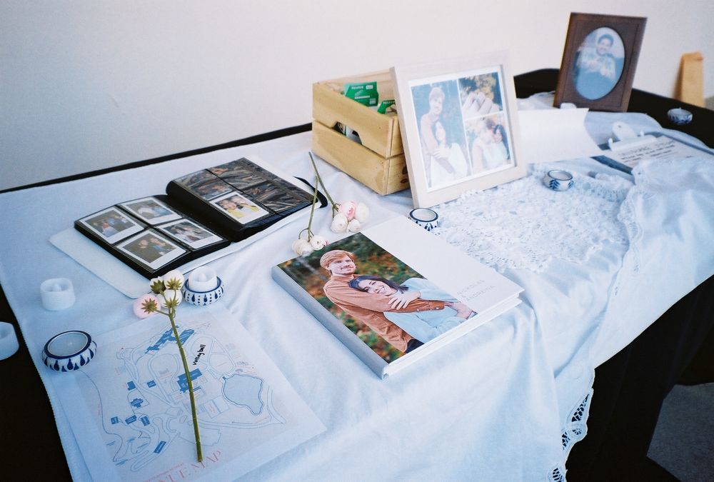 Wedding memory table with framed photos and decorative items on white tablecloth.