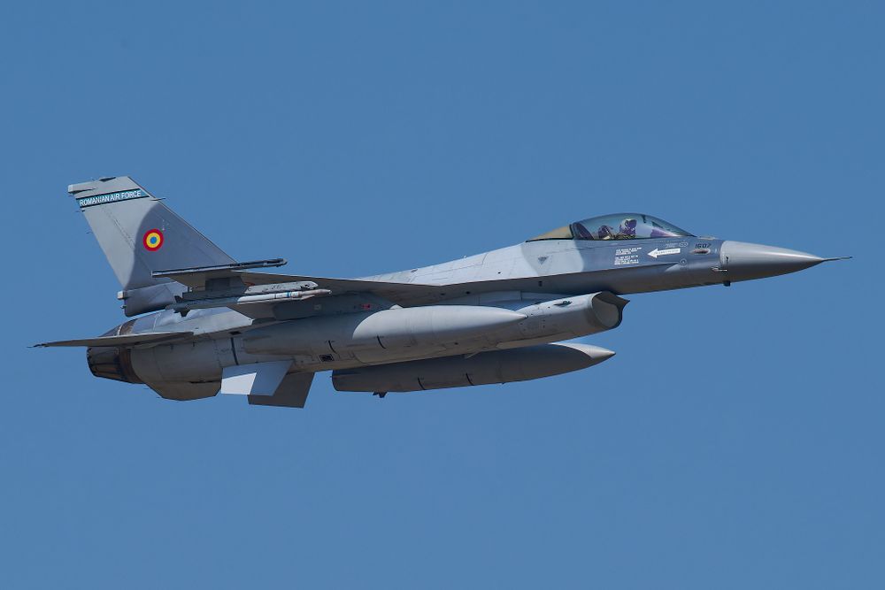 F-16 Fighting Falcon military jet flies against clear blue sky.