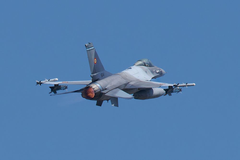 F-16 fighter jet with visible weapons systems photographed during flight.