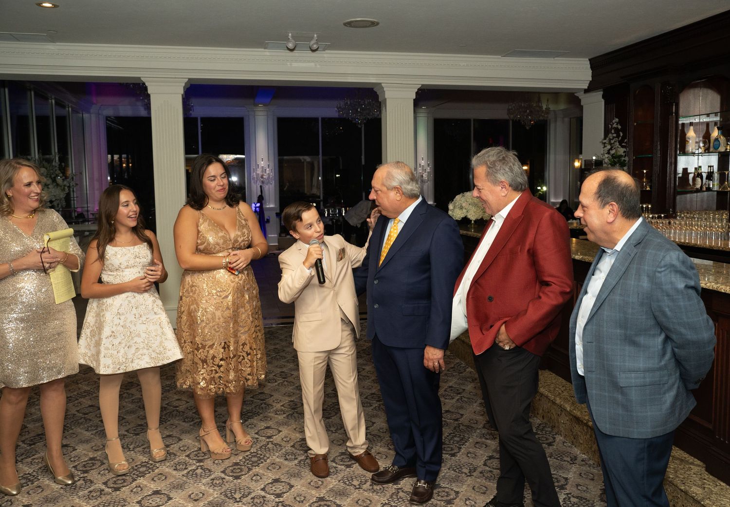 Large group celebrates at indoor event with dance floor and party lighting.
