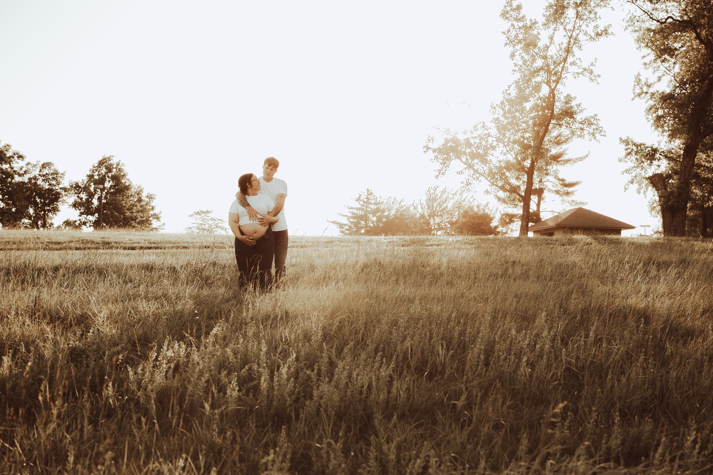 A couple poses on a hilltop during golden hour for romantic photos.