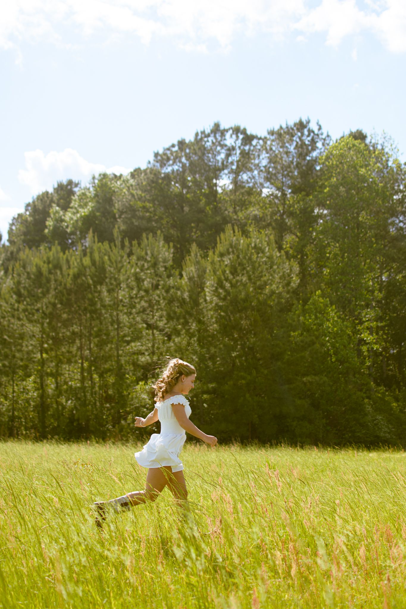 A person runs freely through a tall grass meadow on a bright summer day.