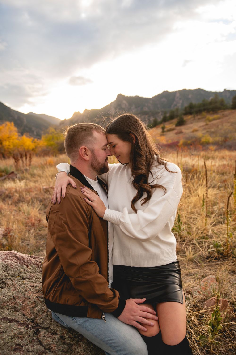 Intimate engagement photo of couple embracing at golden hour in mountain setting.