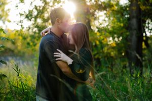 Romantic couple embracing in golden sunlit field during sunset.