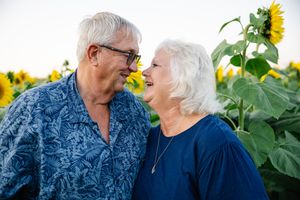 Senior couple sharing loving moment in front of blooming sunflower field.