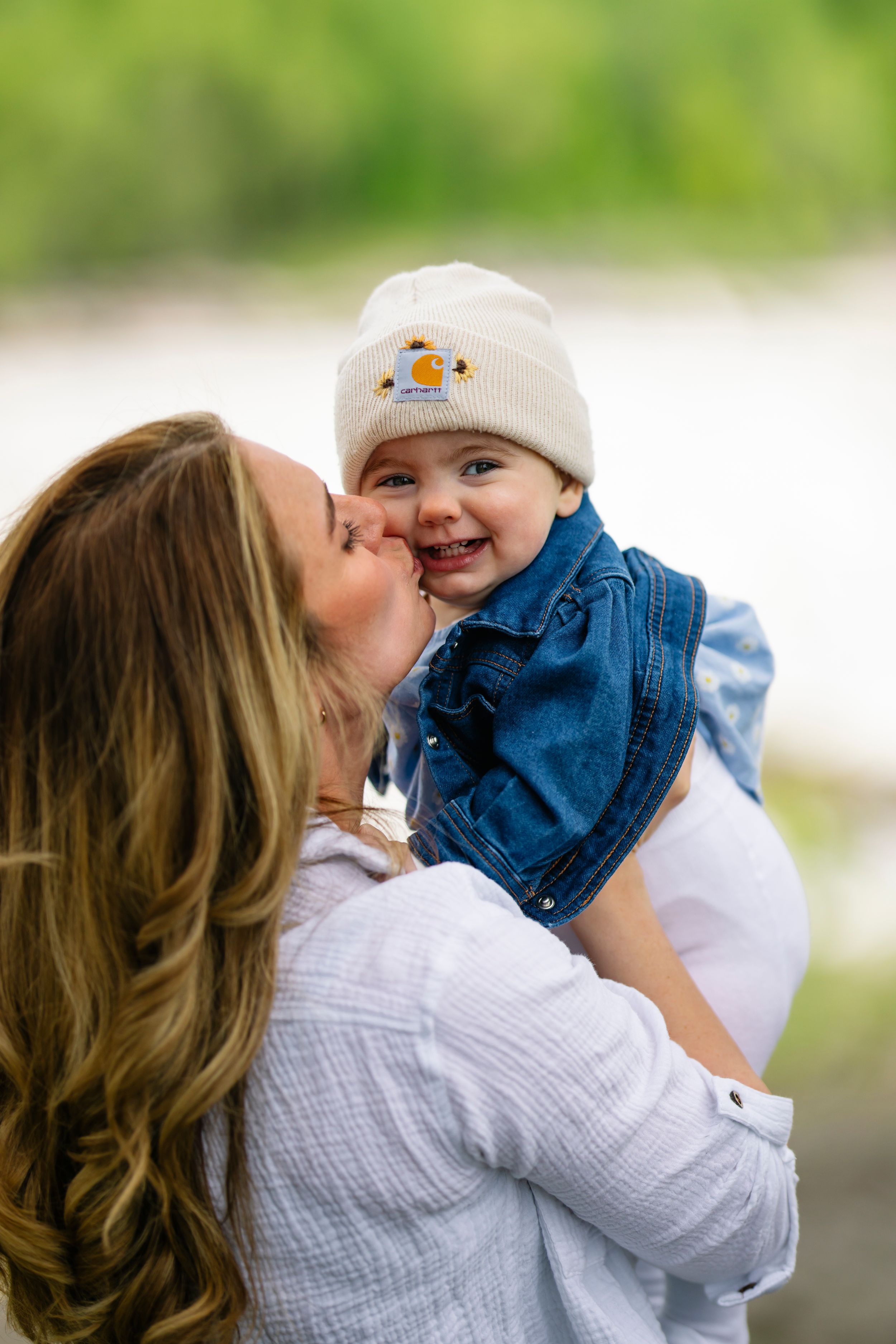 Joyful moment shared between parent and baby wearing winter hat outdoors.