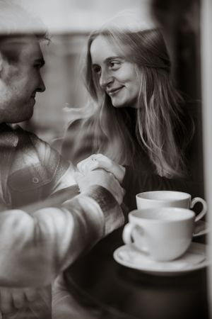 Intimate coffee date scene with cups of coffee and two people sharing a romantic moment.