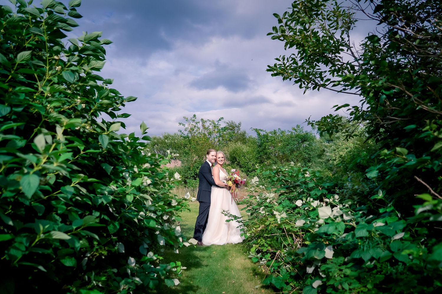 Wedding photo of a couple posing among rosehips in the middle of the woods in St. John's, Newfoundland.