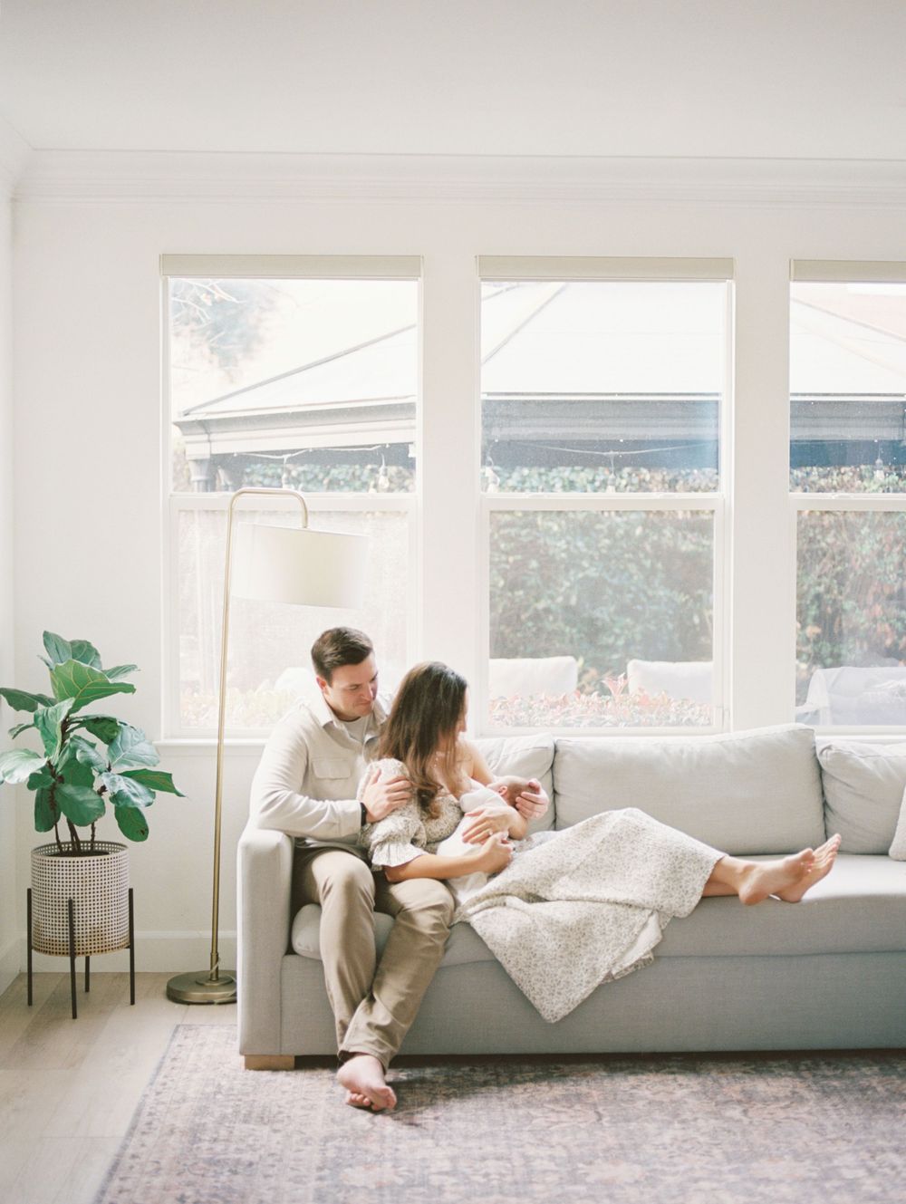 A series of four lifestyle photos showing people relaxing on a white sofa in a bright, modern living room with large windows.