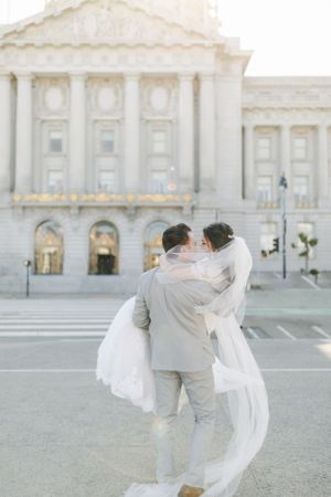 A romantic wedding couple embraces on the steps of San Francisco City Hall's grand Beaux-Arts architecture.Film by Chelsee Rawe Photography