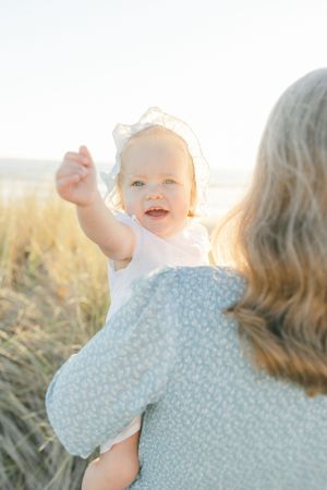 Baby in a bonnet raising her arm at the beach session filmed and caught by Chelsee Rawe
