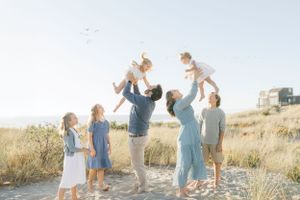 Family picture taken by Chelsee Rawe of a family of seven with two babies being thrown in the air