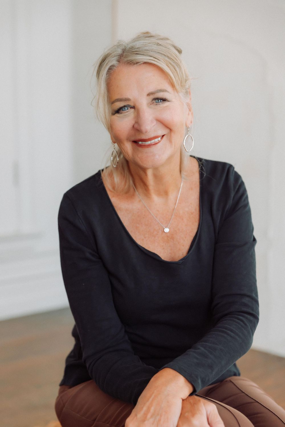 Professional portrait series showing a person in a black top against a light background, displaying warm expressions.