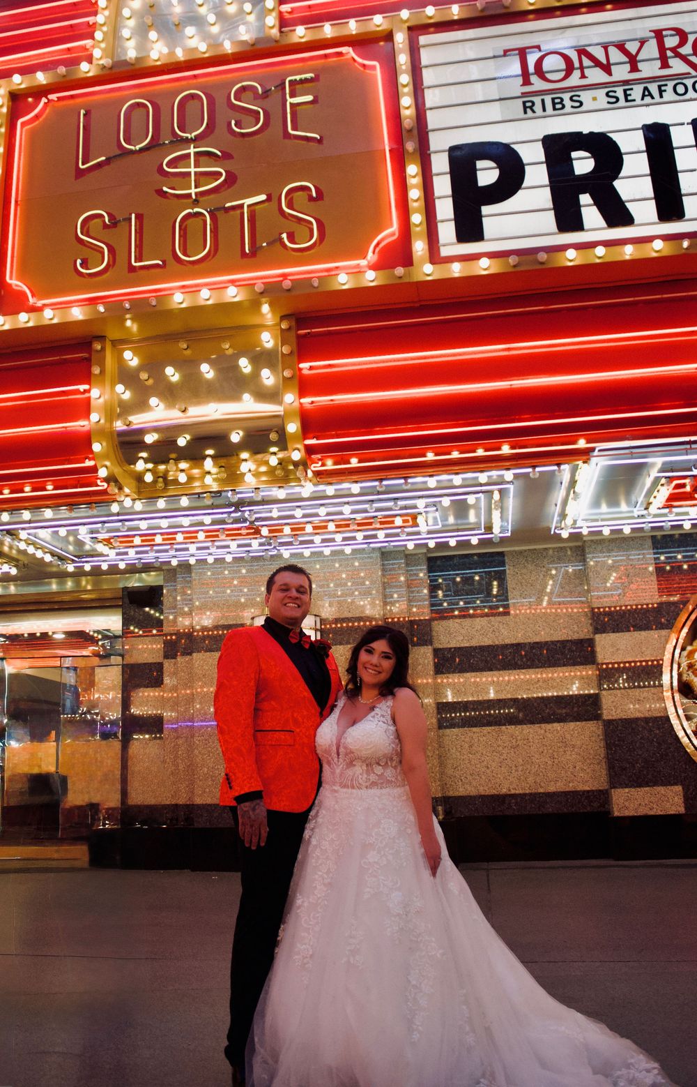 Wedding couple standing under Loose Slots neon sign at Fremont Street in Las Vegas.