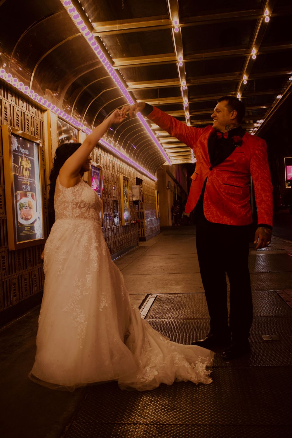 Couple sharing a romantic dance under warm Edison bulb lights in a Vegas arcade tunnel.