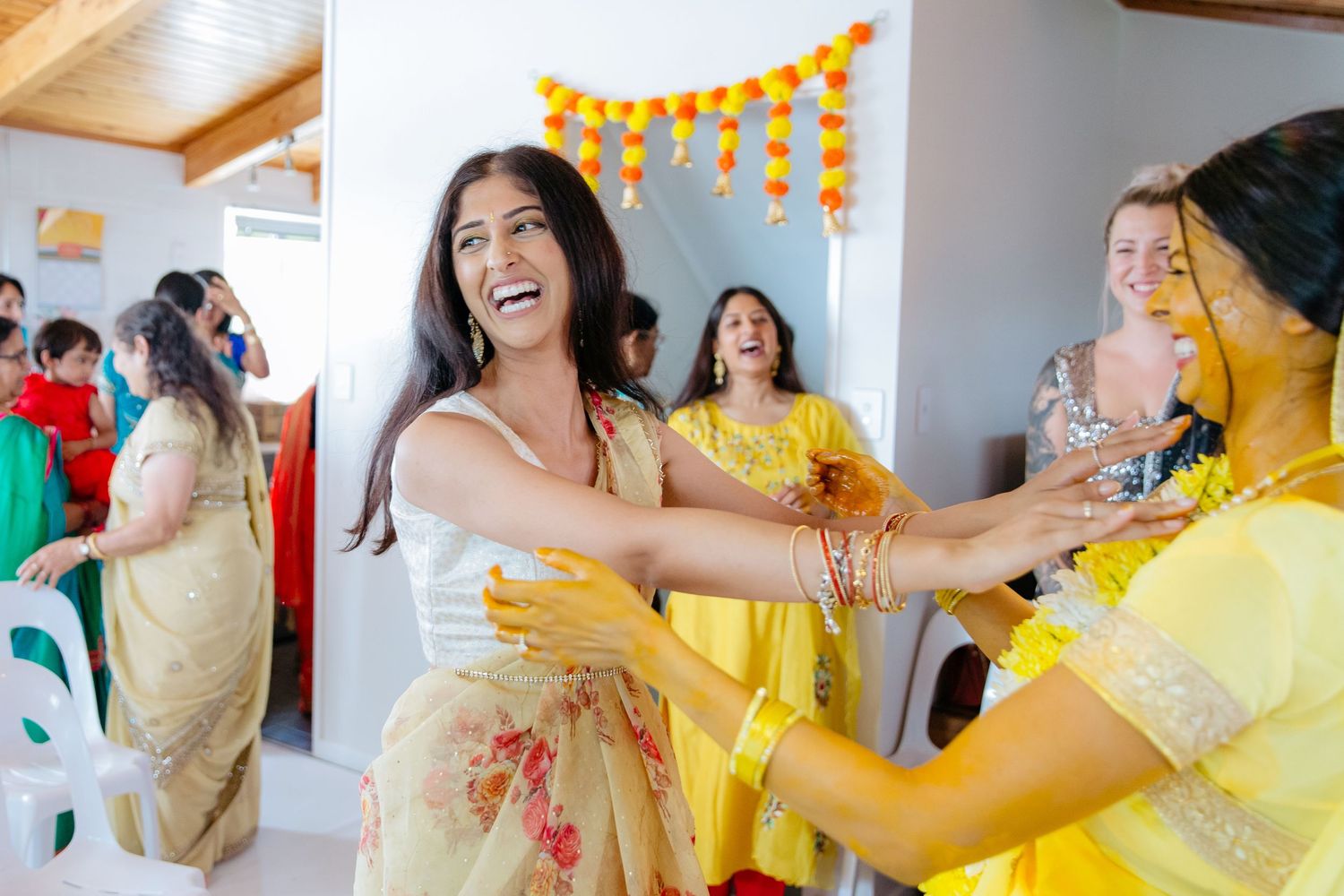 Haldi ceremony from Indian wedding with Bride having turmeric applied by friend