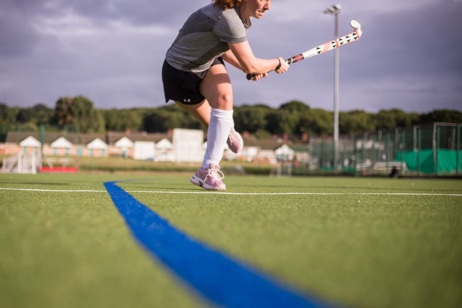 Artistic photo of a hockey player having played the ball with blue line sweeping through the pitch on the astroturf.