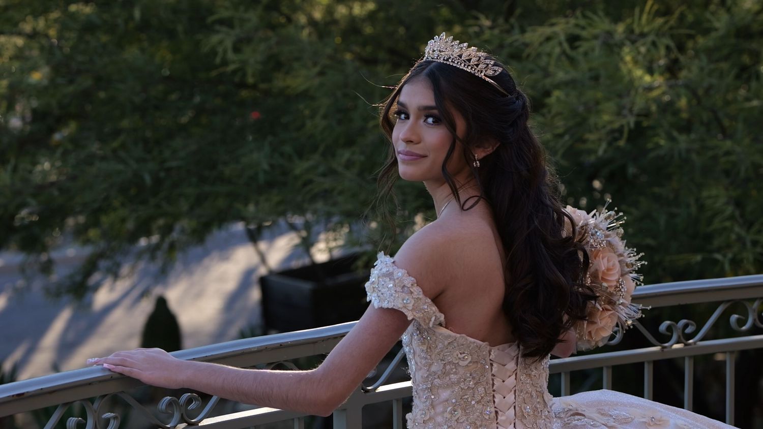 Elegant ball gown dress with tiara photographed outdoors on stone balcony.