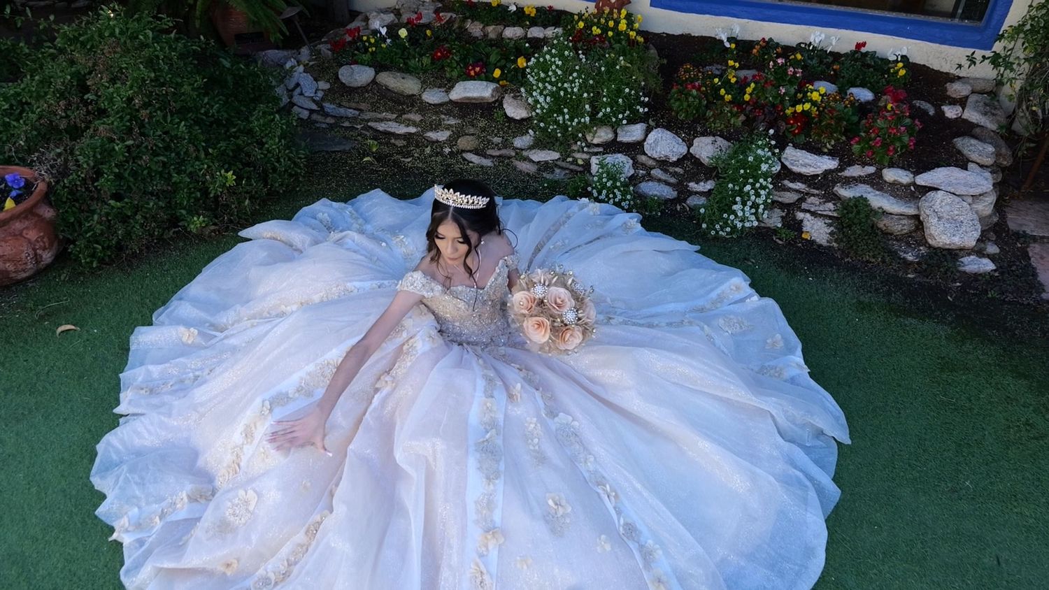 Aerial view of flowing white ball gown spread out on garden lawn.