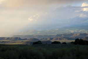 Dramatic sunset landscape over rolling hills and distant mountains.