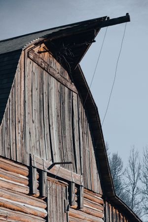 Weathered wooden barn with dramatic angular roof against overcast sky.