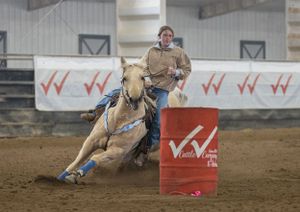 A horse and rider navigate around a red barrel during a competitive rodeo event.