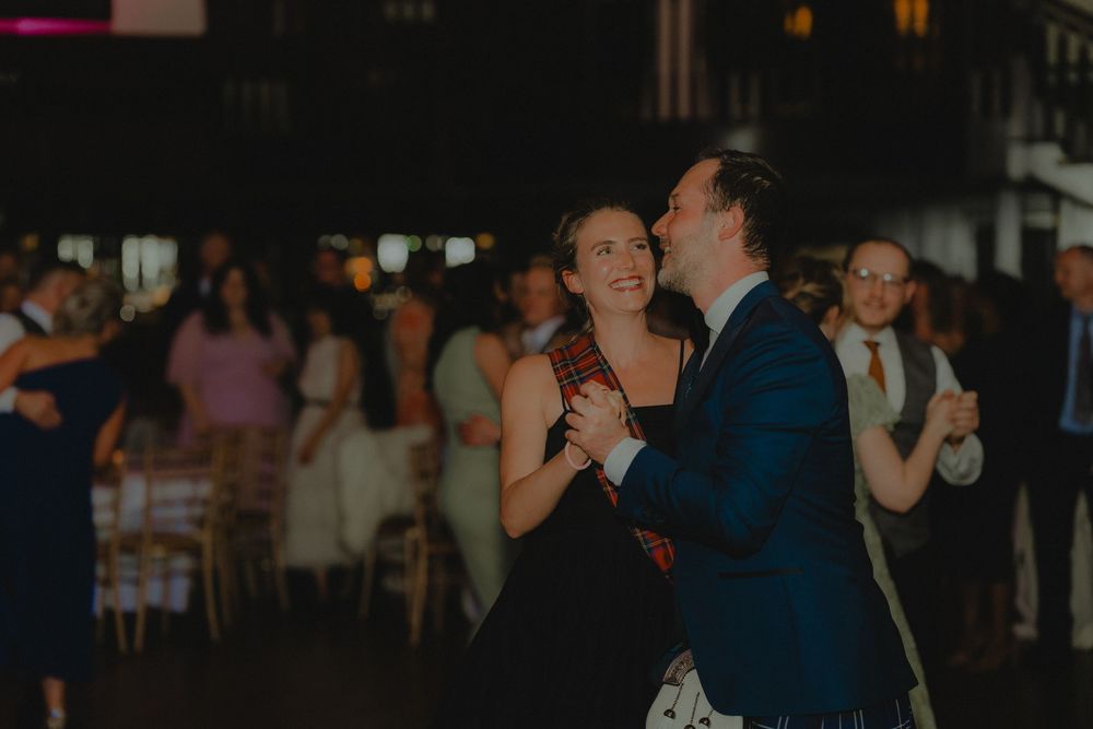 Couple sharing a romantic first dance at an elegant wedding reception with guests in the background.