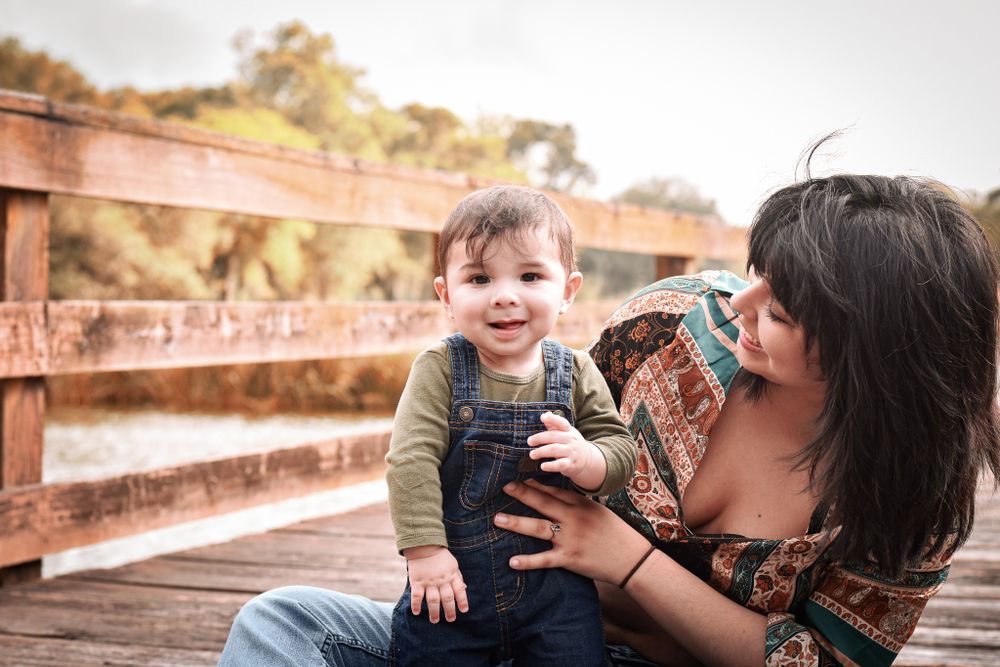 Candid moment between parent and child sitting on wooden boardwalk.