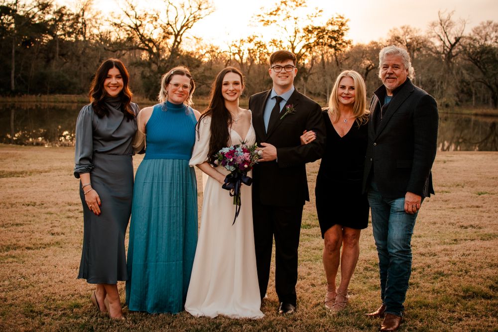 Wedding group photo at sunset with coordinated formal attire.