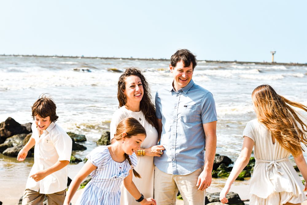 Family enjoying casual beach day together in light summer clothing.