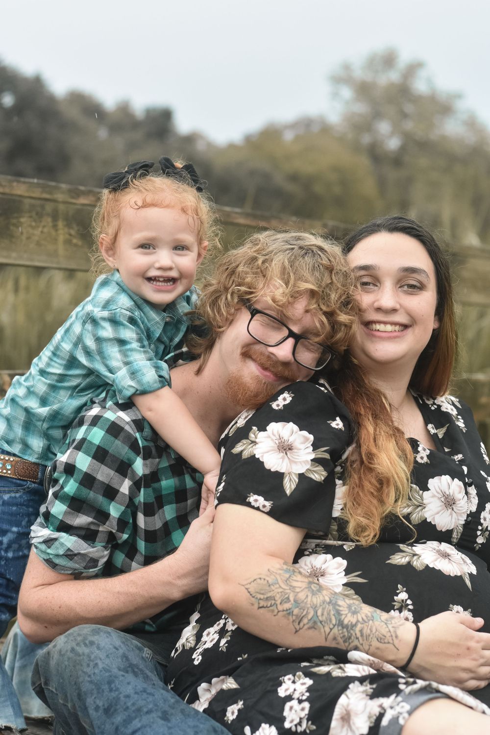 Happy family portrait outdoors with matching plaid shirts and floral dress.