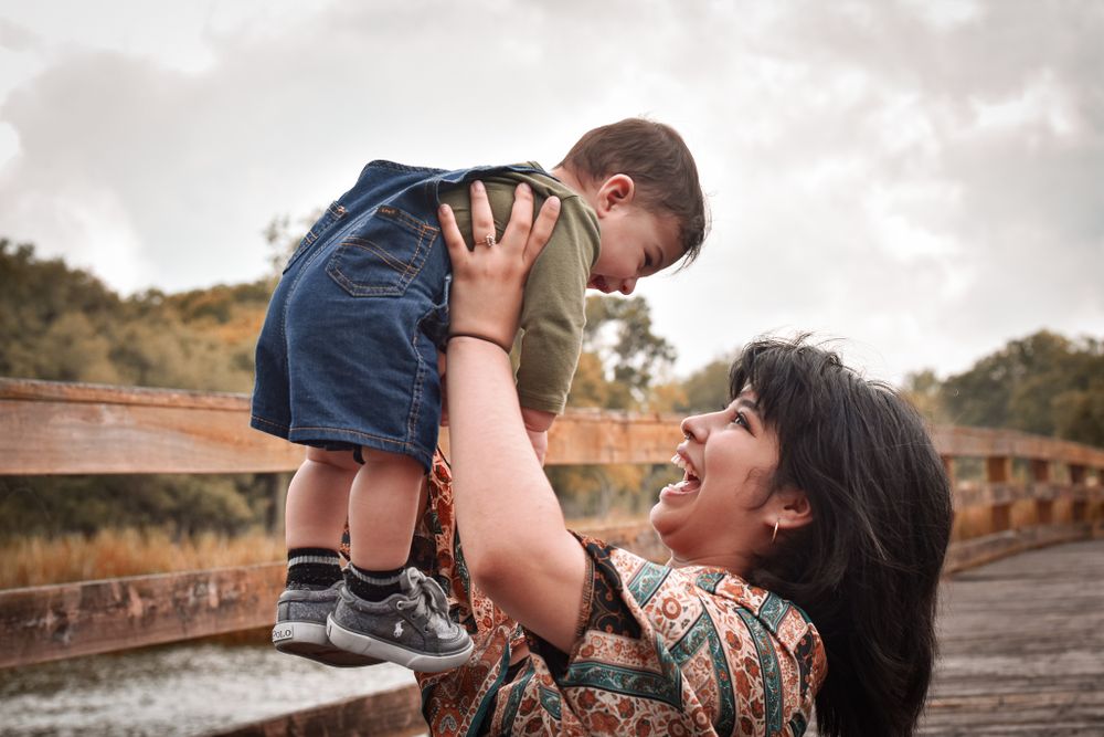 Joyful moment between parent and child playing on wooden boardwalk.