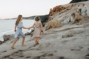 People walking along a rocky coastal beach path at dusk.
