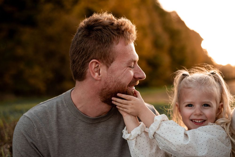 Heartwarming outdoor family moment captured during golden hour with playful interaction between adult and child.